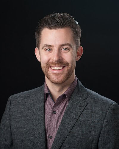 Headshot profile picture of smartly dressed business man against black background