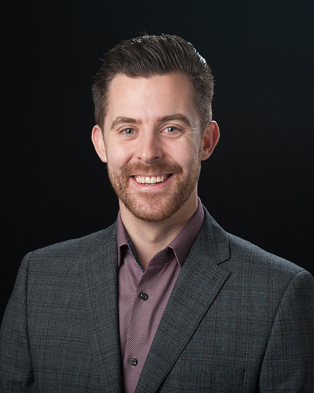 Headshot profile picture of smartly dressed business man against black background