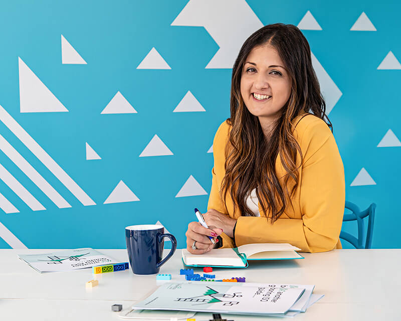 Personal branding photograph of young woman business trainer surrounded by training materials including lego bricks