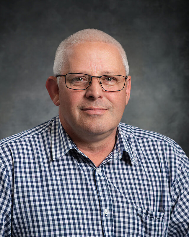 headshot of company director in check shirt against a mottled grey background